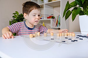 A 4-year-old boy plays loto, studies numbers using a board game. Place for text. photo