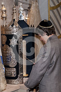 14 year old boy practicing for his Bar Mitzvah reading Torah scroll