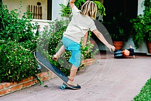 5 year old boy practicing skate in his backyard, stumbling and falling to the ground photo