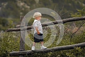 A 4-year-old child climbs a wooden old fence