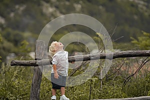 A 4-year-old child climbs a wooden old fence