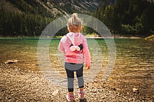 2-3 year old child with diper standing at Gruner see, Green lake rocky shore