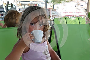 A 4 year old girl drinks a decaf in a Toroni bar in Greece photo