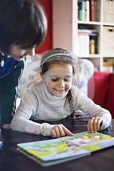 5 year old girl looks at a book with figures