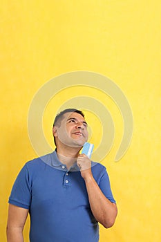 40-year-old Latino man shows his credit or debit card happy to use it in discounts and promotions in store and online purchases photo