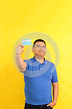 40-year-old Latino man shows his credit or debit card happy to use it in discounts and promotions in store and online purchases photo