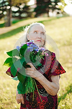 80 year old woman with a bouquet of flowers in her hands.