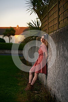 25-year-old woman with pin-up style, leaning on a stone wall