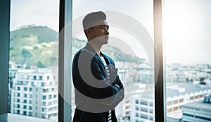 This year were going to be bigger and better. a young businessman looking thoughtfully out of an office window.