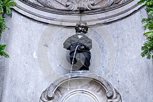 The 400 years Birthday of Famous statue of The Manneken Pis, Brussels, Belgium. Peeing Boy in Suite and Birthday Cake