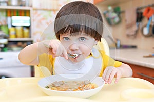 2 years boy eating soup with meat balls at home kitchen