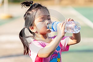 A 3-4 years old girl was drinking water to quench her thirst due to the hot weather. Kid sweat on their faces.