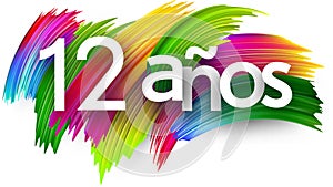 12 years at spanish paper word sign with colorful spectrum paint brush strokes over white photo