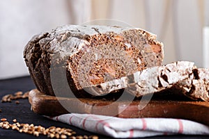 Yeast free homemade sliced bread with whole rye and wheat grains on black wooden background