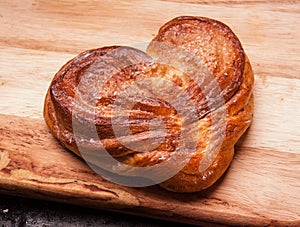 Yeast sweet buns in the shape of a heart on a Board on black baking tray. Country house style. Authentically
