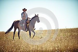 Yeeha. Full-length portrait of a mature man on a horse out in a field.