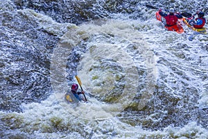 Yekaterinburg, Russia - June 8, 2019: Extreme whitewater rafting trip. A group of people team in kayaks practise traversing the