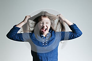 A yelling teenage girl oulling her hair apart over white background