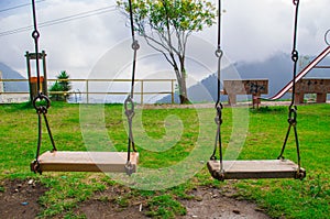 Yelllow colored playground swing located in Andes mountains Ecuador, spectacular green background and blue sky