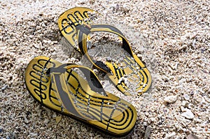 Yelloe rubber slippers on sand beach