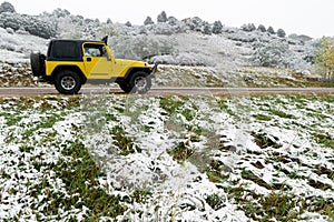 Yellow 4x4 jeep on snow covered mountain road