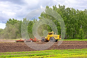 Yellow agricultural machine plows a field, harrows and cultivates the soil for sowing grain. The concept of agriculture