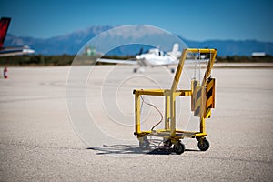 A yellow aircraft chocks and fire extinguisher carrier on a small airport.