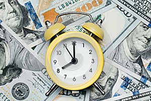 Yellow alarm clock on the stack of one hundred american dollars bills. Credit, deposit and mortgage concept.