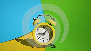 Yellow alarm clock on a yellow and blue colorful background