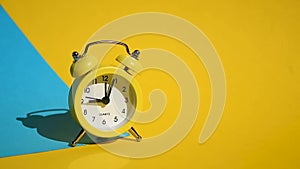 Yellow alarm clock on a yellow and blue colourful background, Deep shadows