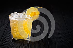 Yellow alcohol cocktail with cherry and lemon on black background