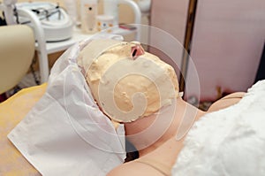 Yellow alginate mask on a woman face in a cosmetology clinic