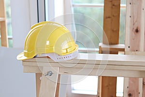 Yellow antiknock helmet on wooden table at carpentry woodwork workshop, personal protective equipment PPE at work place concept