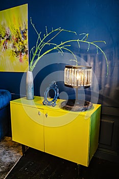 Yellow antique bedside table in a blue interior