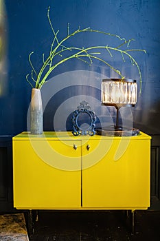 Yellow antique bedside table in a blue interior