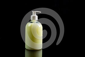 Yellow antiseptic liquid soap in a bottle with a dispenser on a black background. Side view, close-up. Horizontal orientation