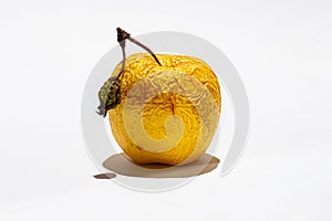 Yellow apple with ponytail with shriveled dry skin on white background