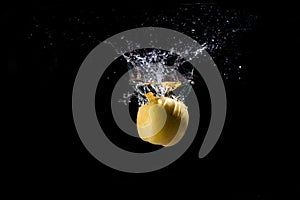 Yellow Apple in splashes of water on a black background