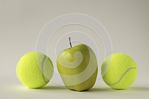 Yellow apple between two tennis balls