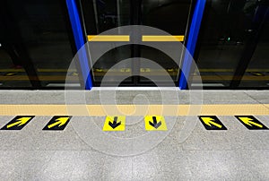Yellow arrow marks on the floor of subway platform