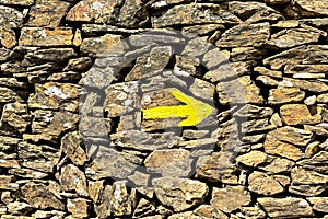 Yellow arrow on the old wall, direction indicator on the pilgrim routes The Way of Saint James