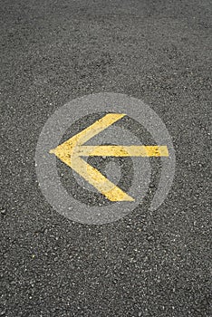 Yellow arrow sign painted on asphalt or road