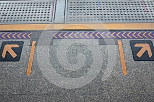 Yellow arrows symbol on platform in queue waiting for train at sky train station, Sign for train`s passenger.