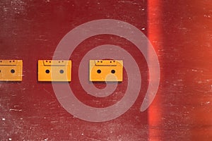 Yellow Audio Cassettes Tapes On Red Background, Top View Toned And Scratches. Creative Concept Of Retro Technology