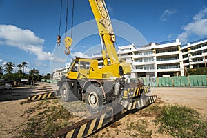 Yellow automobile crane with risen telescopic boom outdoors. Mobile construction crane on a constructin site. Crane