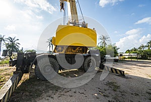 Yellow automobile crane with risen telescopic boom outdoors. Mobile construction crane on a constructin site. Crane
