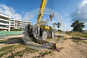 Yellow automobile crane with risen telescopic boom outdoors. Mobile construction crane on a constructin site. Crane