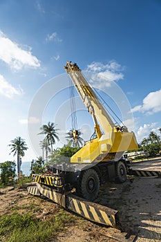 Yellow automobile crane with risen telescopic boom outdoors. Mobile construction crane on a constructin site. Crane