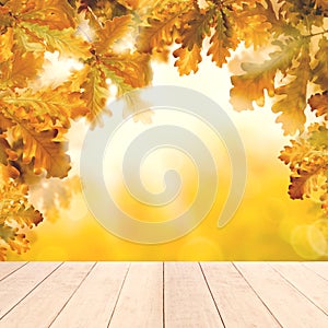 Yellow autumn background with white empty wooden table and fall oak leaves