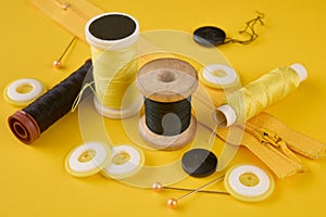On a yellow background are different spools of black and yellow thread